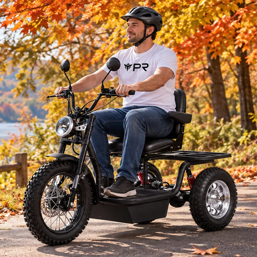A helmeted rider wearing a white Punk Ride logo T-shirt rides the MotoTec Electric Trike 60V 1800W in an autumn setting. Mobile collection banner.