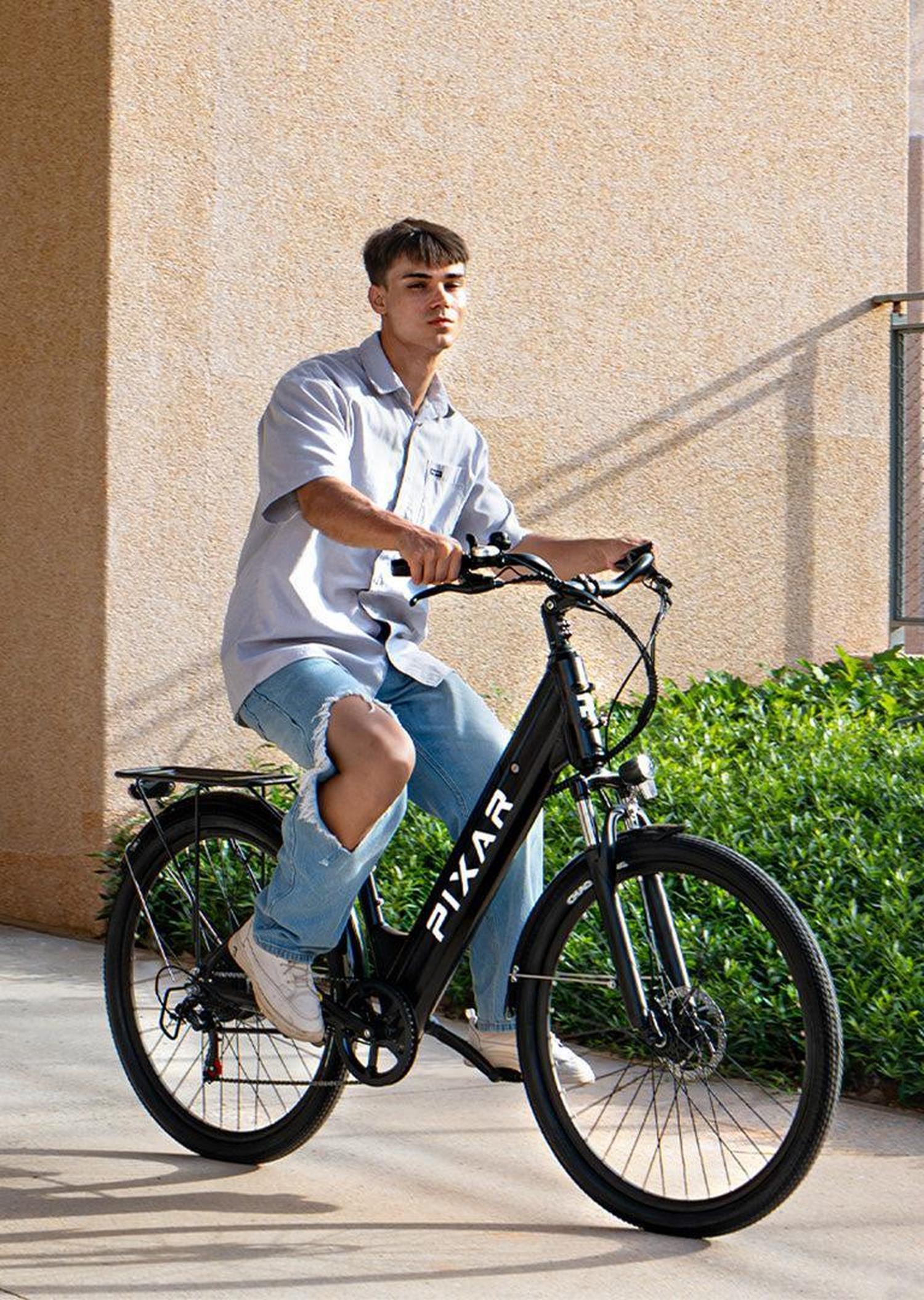 Person riding a black electric bike with 'Ryker' branding on a sidewalk.