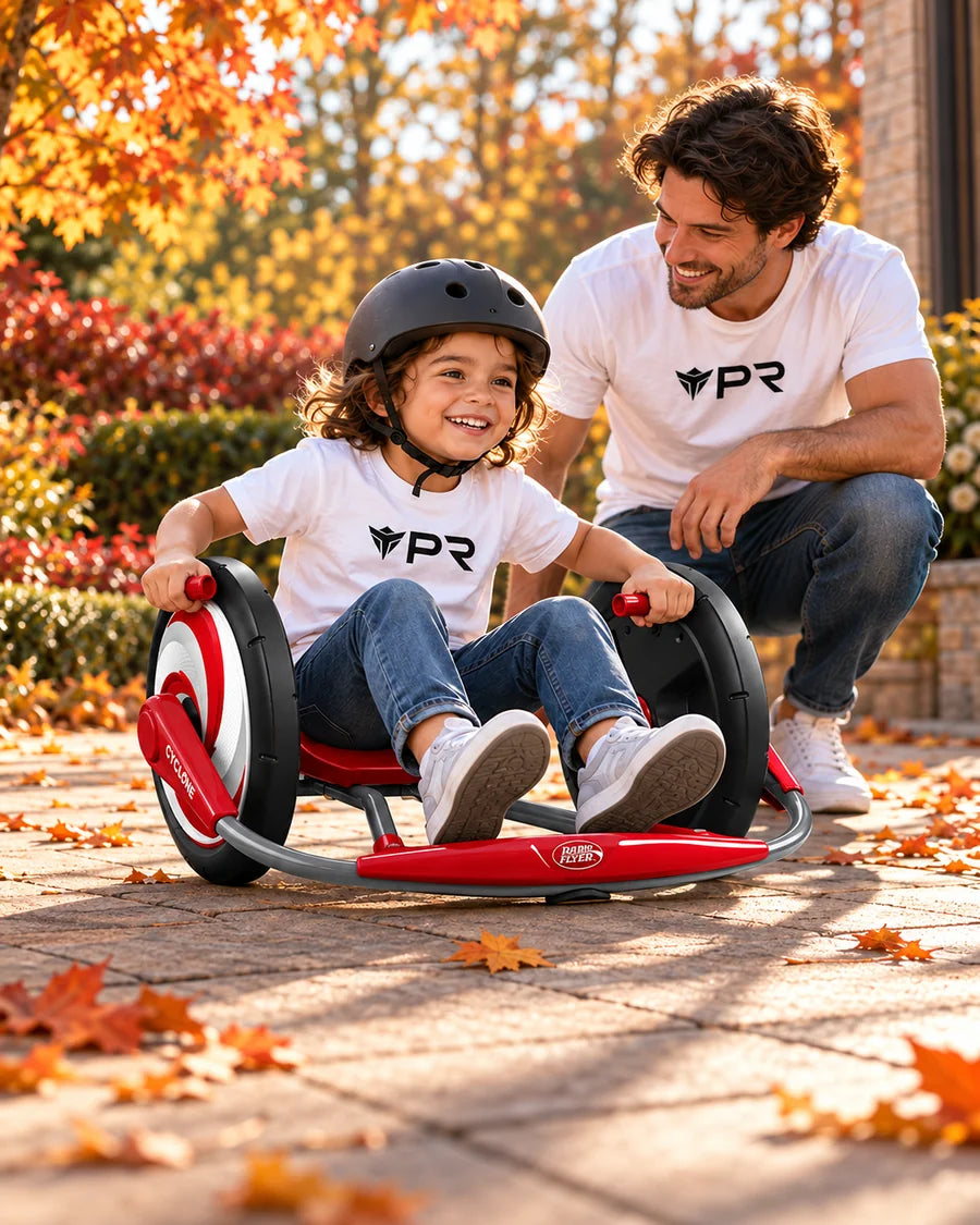 A helmeted child uses a red Radio Flyer Cyclone ride-on toy beside an adult in white Punk Ride logo T-shirts on an autumn path.