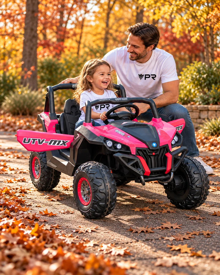 A child sits in a pink Mini Moto UTV ride-on toy beside an adult in white Punk Ride logo T-shirts on an autumn path.