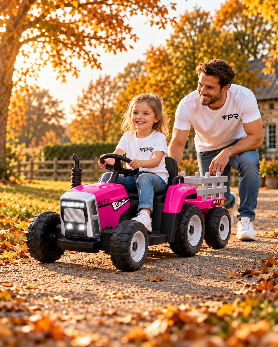 A child uses a pink ride-on tractor with a trailer beside an adult in white Punk Ride logo T-shirts on an autumn farm path.