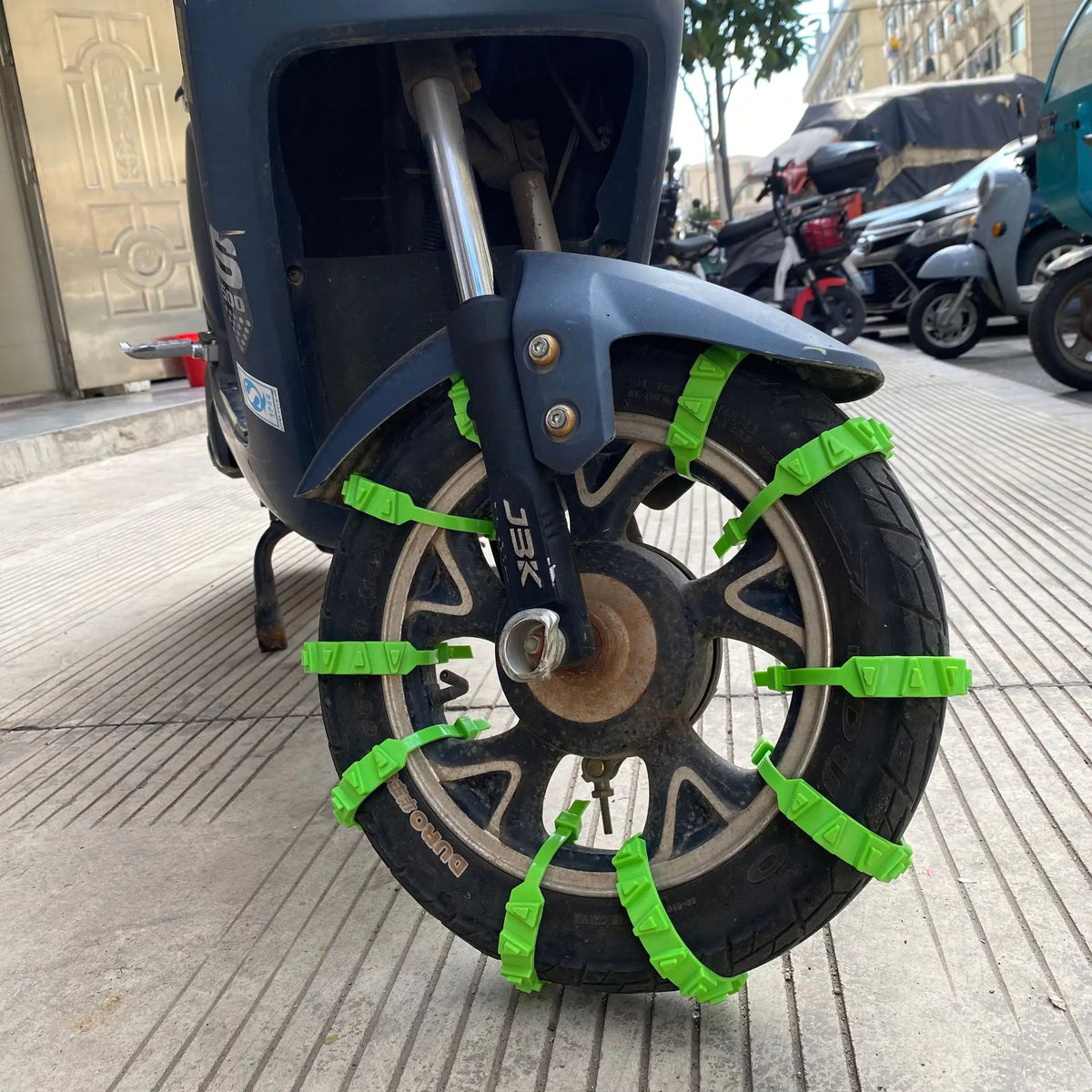 Green nylon tyre straps installed on a scooter tyre; fitting reference